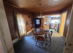 dining room with a patio door on the left and a chandelier hanging over a four chair kitchen table. Leads into the kitchen